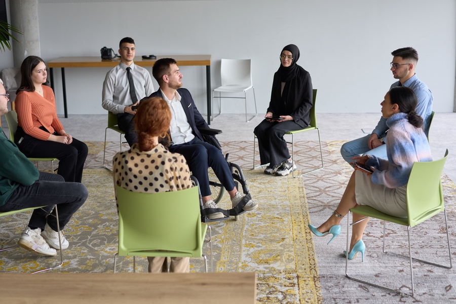 Corporate business team meeting with a manager or coach. Group of happy diverse, multiracial people sitting in a circle .