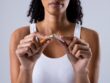 Midsection of african american mid adult woman breaking cigarette against white background. addiction, smoking, quit, cancer and healthcare concept.